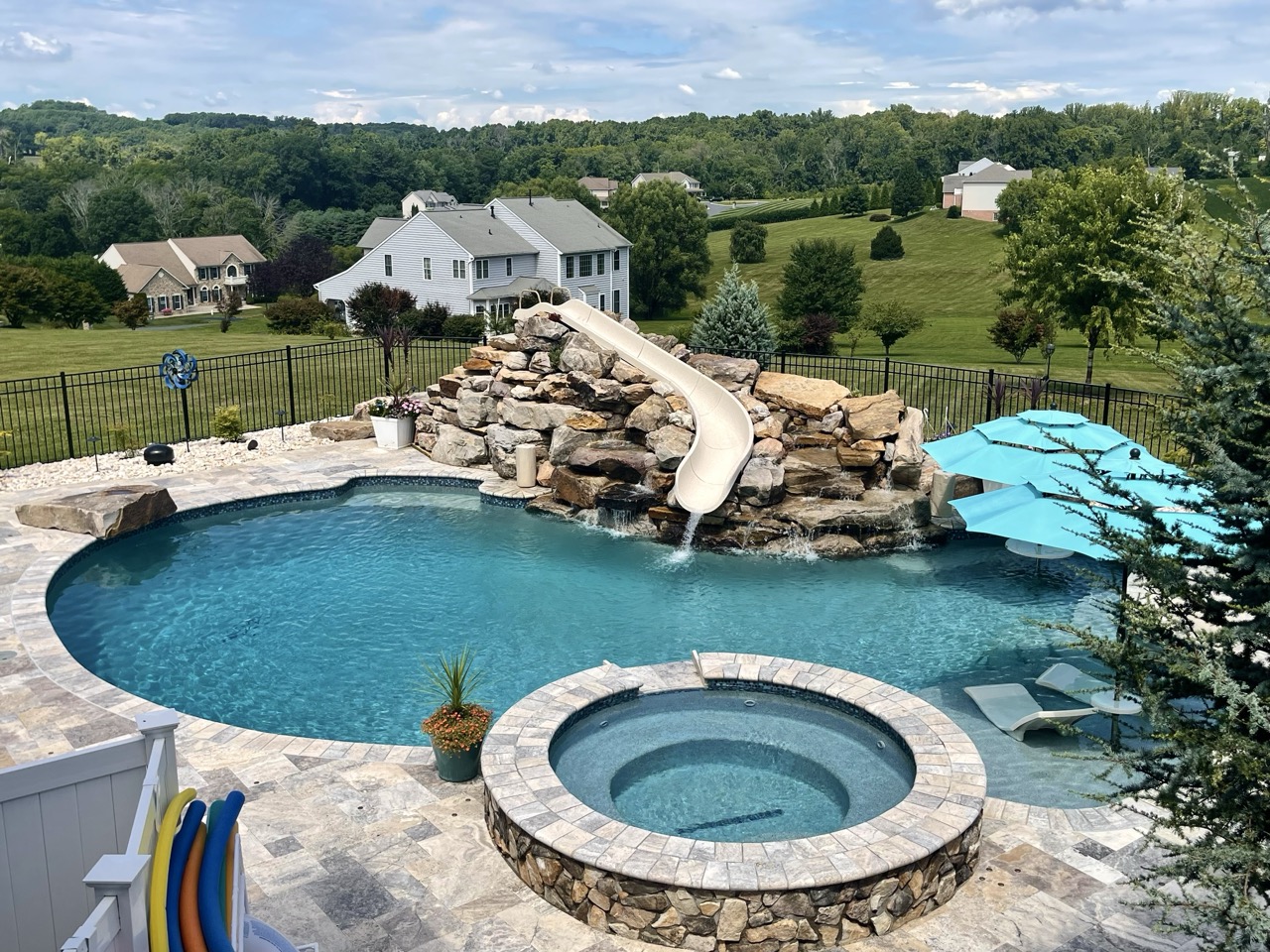 Luxury backyard pool in Harford County with rock slide and spa, designed by Woodfield Outdoors.