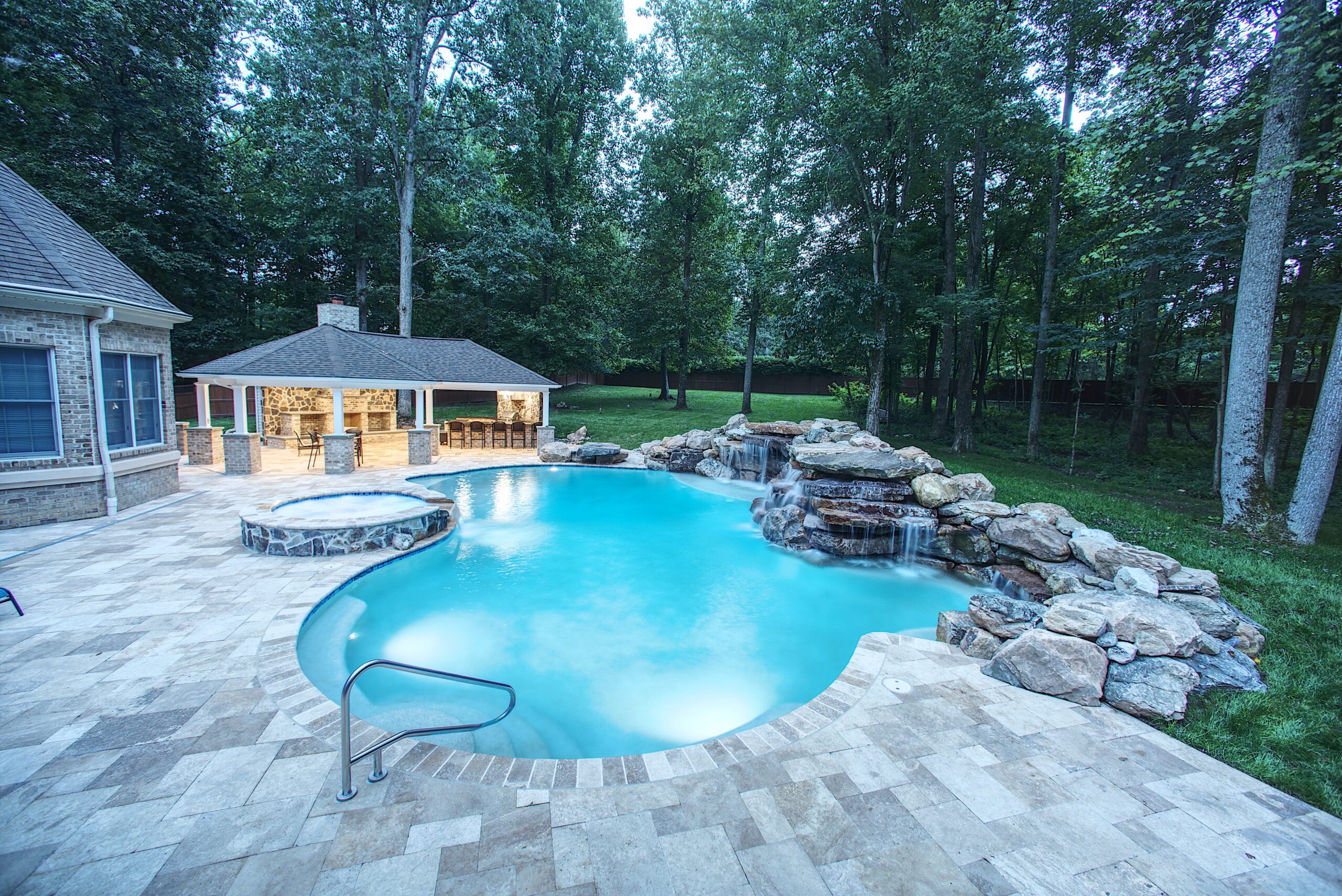 A completed pool renovation that includes a paver patio, spa, and cabana.